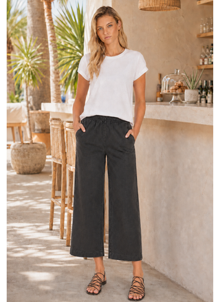 Woman wearing a white t-shirt and black wide-leg pants standing in a casual outdoor setting.