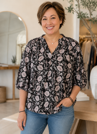 Woman wearing a floral blouse and jeans in an indoor setting
