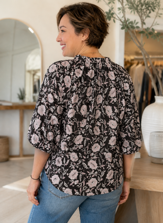 Back view of the Dylan Jolie Cotton Esme Blouse showcasing the high-low curved hemline, relaxed fit, and black floral cotton fabric pattern.