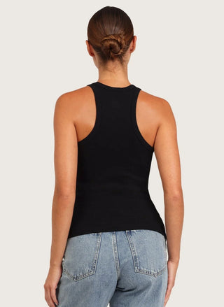 Rear view of a woman wearing a black racerback tank top and light blue jeans against a light gray studio background.