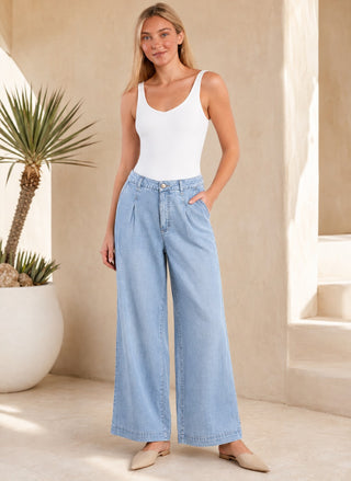 Model wearing light wash Hint of Blu Tencel Wide Leg Trousers paired with a white scoop-neck bodysuit and nude pointed mules.