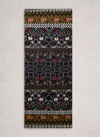 A long rectangular textile runner with an intricate multicolor pattern featuring geometric borders, floral motifs, and a central trellis design, displayed flat against a light textured background.