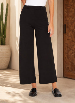 Women in Lyssé Erin High Waist Wide Leg Ponte Pant styled with a white bodysuit and black loafers in a warm Palm Springs-inspired setting.