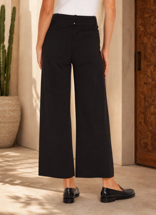 Back view of women’s black high-rise wide-leg cropped pants with patch pockets, styled with a white bodysuit and black loafers.
