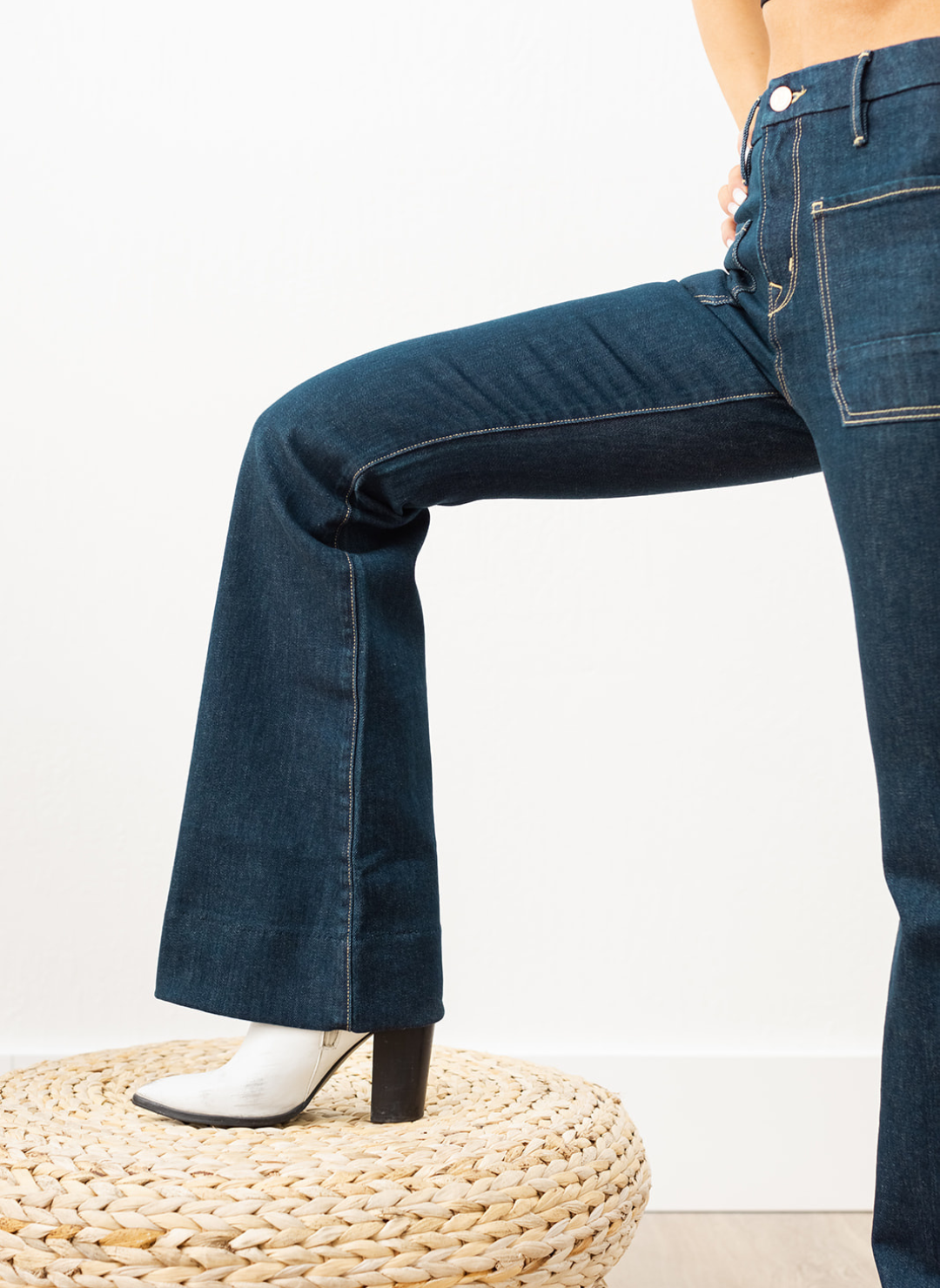 Side view of dark indigo Wanderer Flare jeans showing fitted thigh and true flared leg, styled with heeled boots.