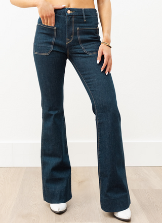 The Wanderer Flare in dark rinse wash with front patch pockets, contrast stitching, and waist-defining rise—women’s flare jeans.