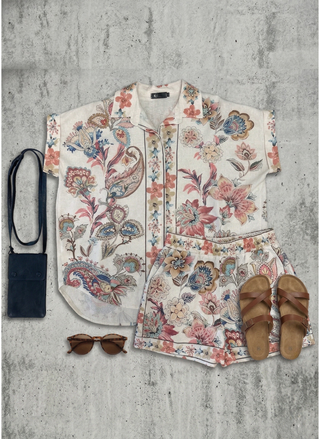 Floral outfit with shirt, pants, sandals, and sunglasses on a textured surface