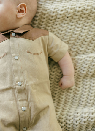 Close up of baby wearing a western onesie.