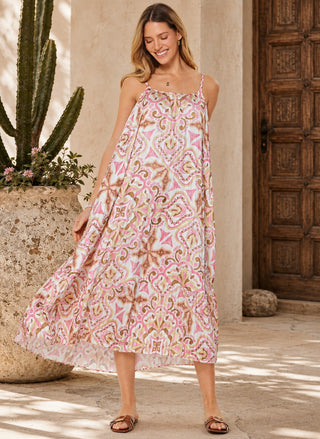 Front view of a model wearing the Current Air Medallion Pleated Midi Dress loosely without a belt, showcasing the flowy tiered pleated skirt and pink geometric print.