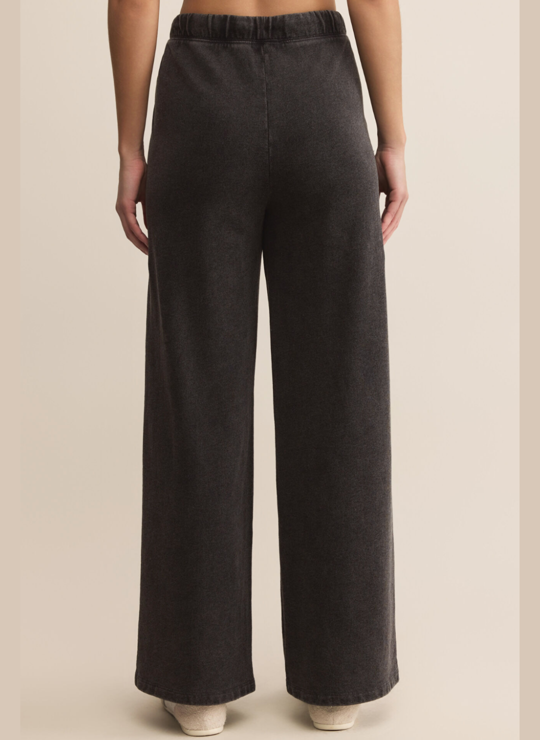 Dark gray wide-leg pants worn by a person on a beige background