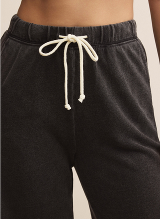Black sweatpants with a white drawstring on a beige background