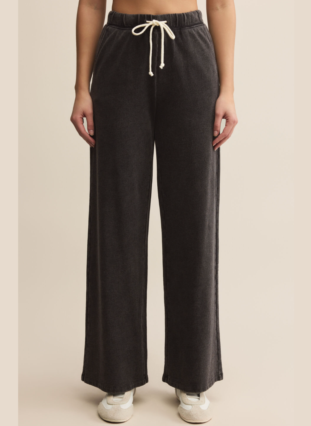 Black wide-leg pants with a drawstring waist on a beige background