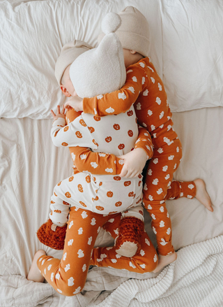 Three children in matching pajamas lying on a bed.
