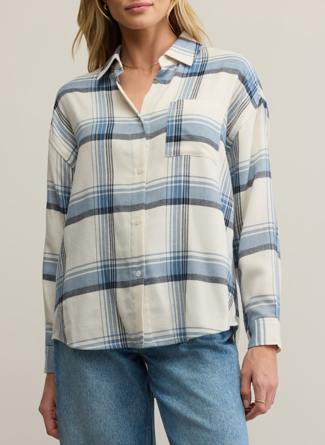 Woman wearing a plaid shirt with blue and white stripes on a neutral background