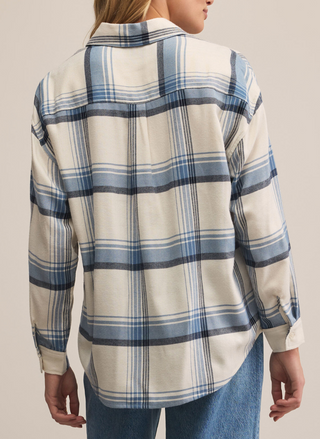 Person wearing a blue and white plaid shirt with a neutral background