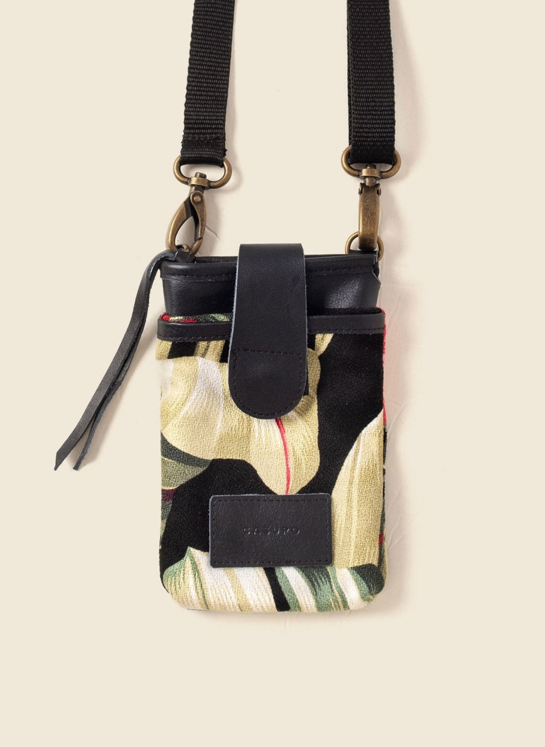 Upcycled tropical canvas and leather crossbody bag with adjustable black strap, brass hardware, and secure zipper closure. Ethically made by Casupo in Los Angeles.