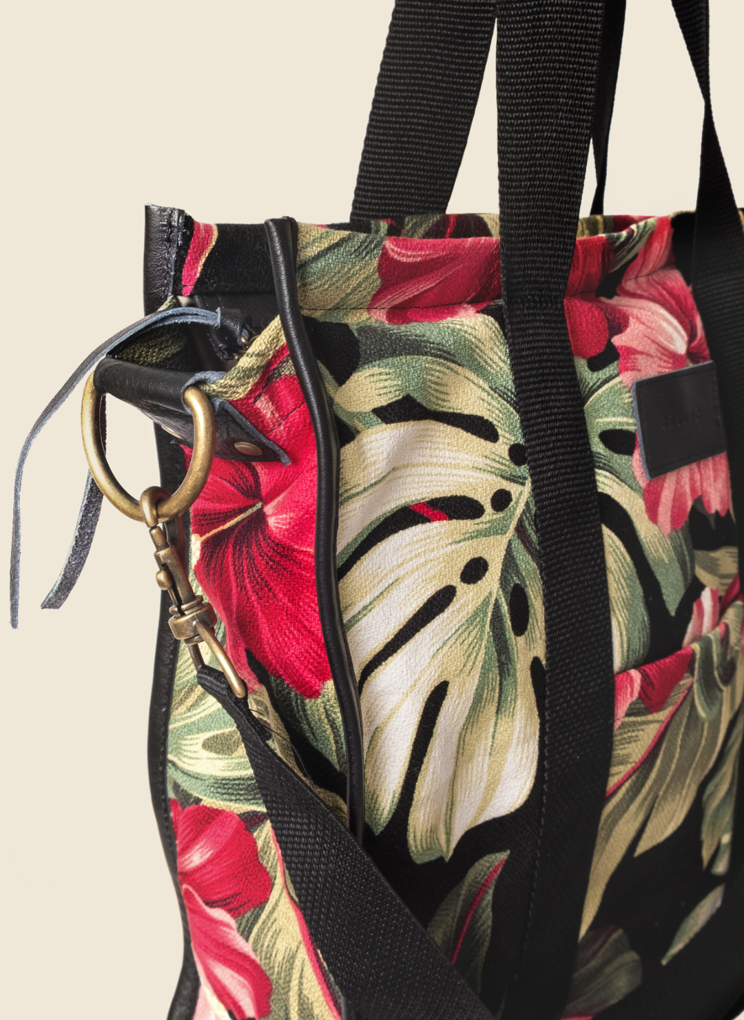 Casupo upcycled canvas and leather tote bag in tropical hibiscus print with interior zip pocket, black straps, and gold-tone hardware; handcrafted in Los Angeles.
