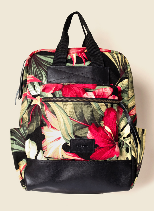 Casupo upcycled tropical hibiscus backpack with black leather base, top handles, bottle pockets, laptop sleeve, and suitcase strap; ethically made in Los Angeles.