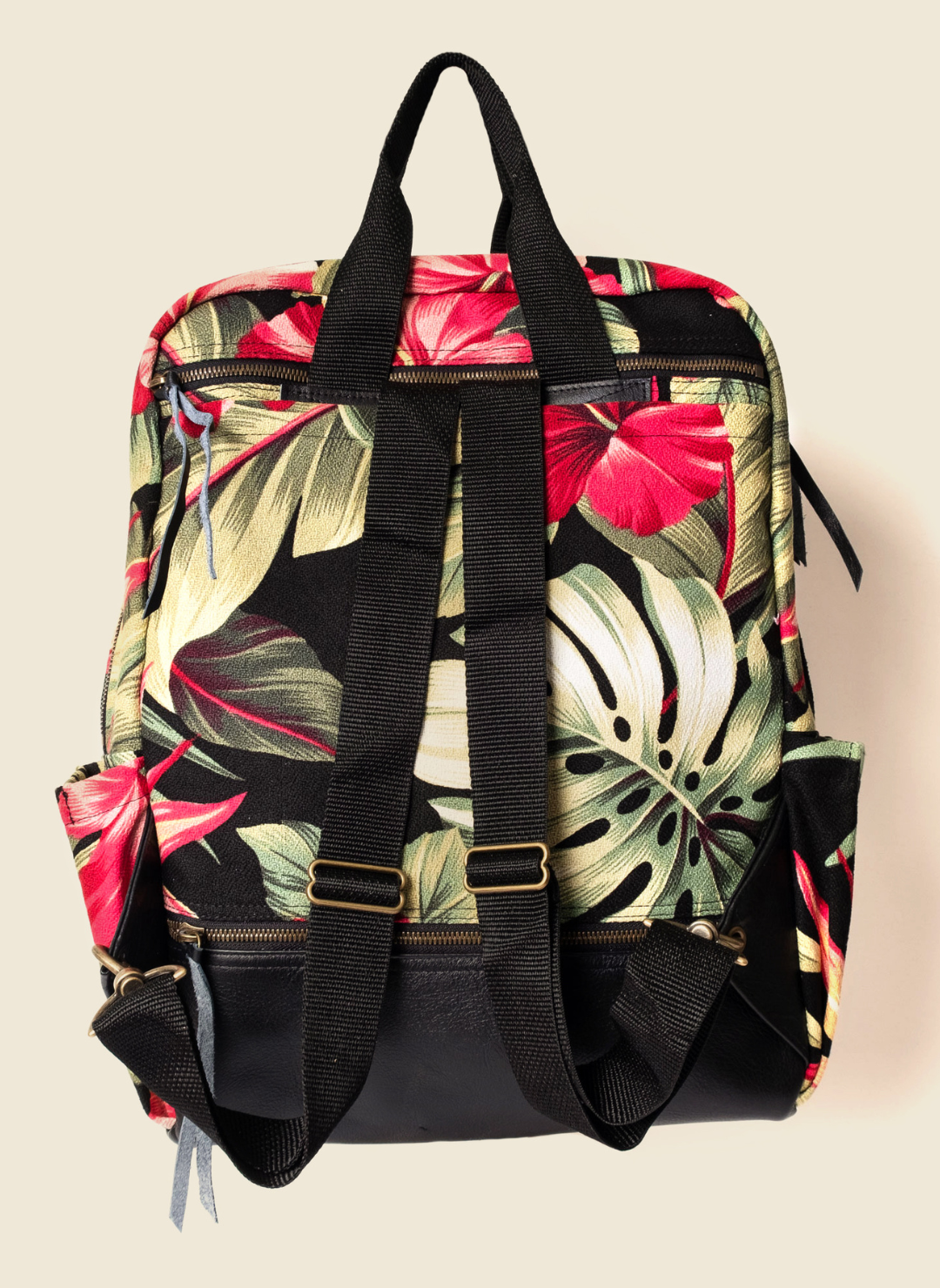 Casupo upcycled tropical hibiscus backpack with black leather base, top handles, bottle pockets, laptop sleeve, and suitcase strap; ethically made in Los Angeles.