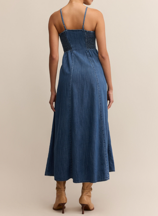Woman wearing Z Supply Angel Eyes Denim Midi Dress with a sweetheart neckline, adjustable straps, front button detail, and flared hem; styled with tan boots.