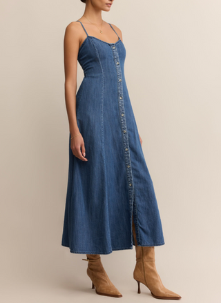Woman wearing Z Supply Angel Eyes Denim Midi Dress with a sweetheart neckline, adjustable straps, front button detail, and flared hem; styled with tan boots.
