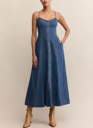 Woman wearing Z Supply Angel Eyes Denim Midi Dress with a sweetheart neckline, adjustable straps, front button detail, and flared hem; styled with tan boots.