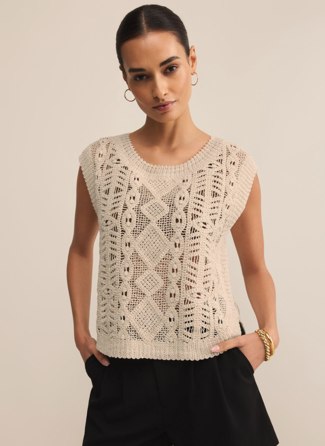 Alt Text: Woman wearing Z Supply Baroque Sweater Top in natural open-knit cotton with baroque-inspired pattern, styled with black shorts by the water.