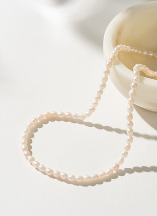 Eloise Necklace featuring freshwater pearls on a 14kt gold-filled 15-inch chain, laid flat on a sunlit white surface for an elegant, minimal look.