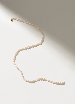Eloise Necklace featuring freshwater pearls on a 14kt gold-filled 15-inch chain, laid flat on a sunlit white surface for an elegant, minimal look.