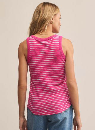 Person wearing a pink striped tank top and blue jeans on a beige background