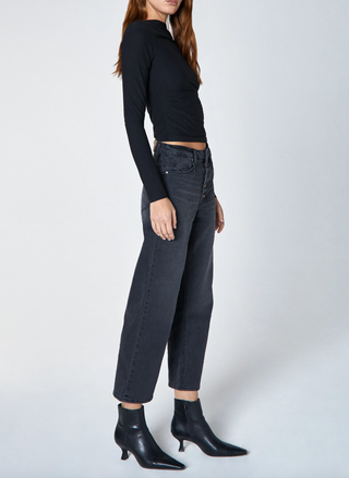 Person wearing a black long-sleeve top and dark jeans on a white background