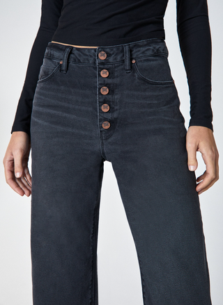 Dark blue jeans with button details on a white background