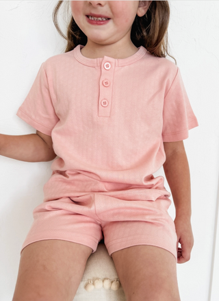 Child wearing a pink outfit with a plain background