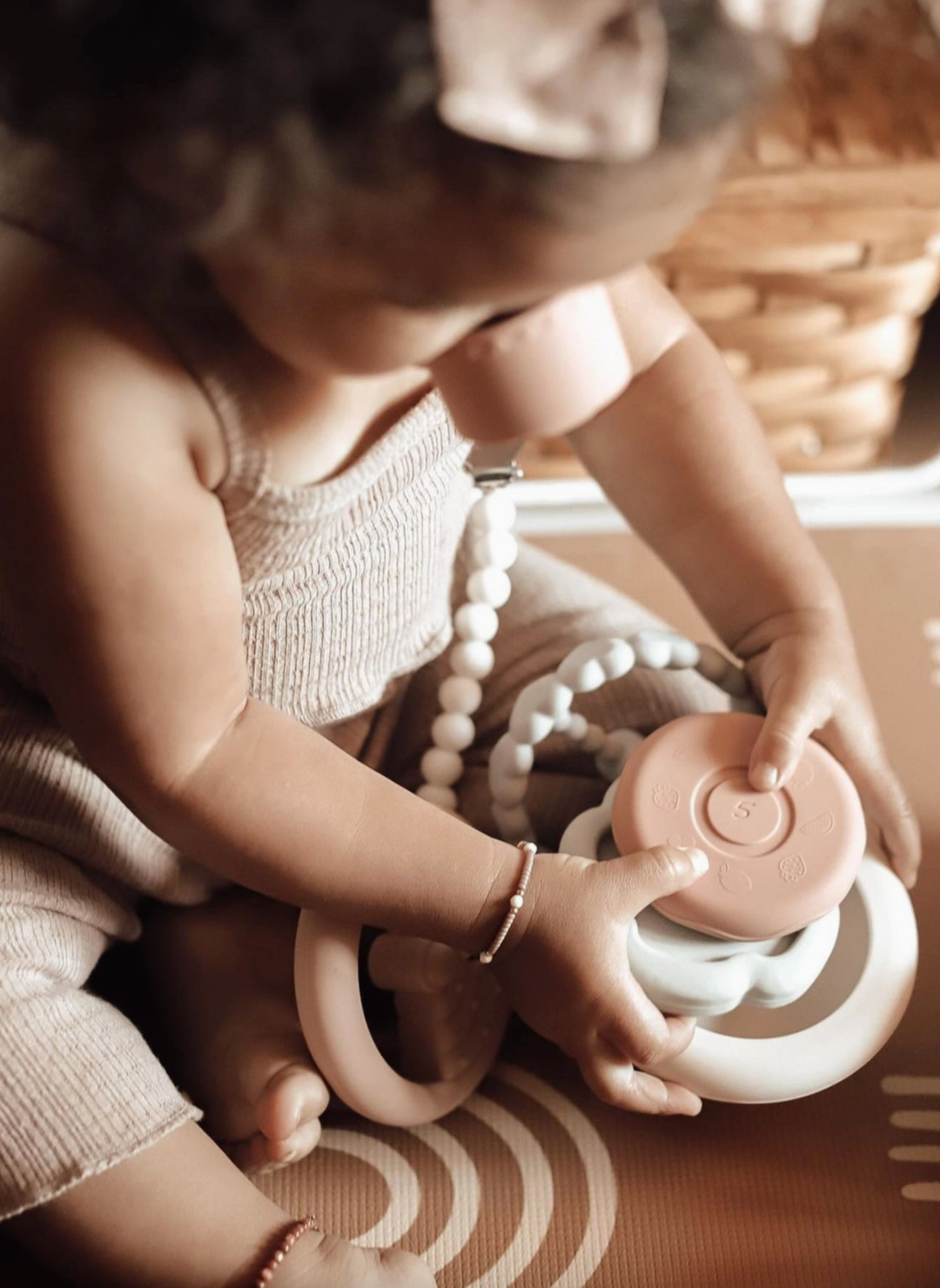 Child playing with a pink toy in a warm-toned room
