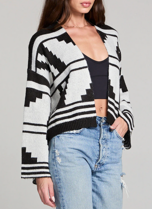 Woman wearing black and ivory Saltwater Luxe Southwest Cardi with geometric print, cropped length, and flared sleeves paired with high-waisted jeans.