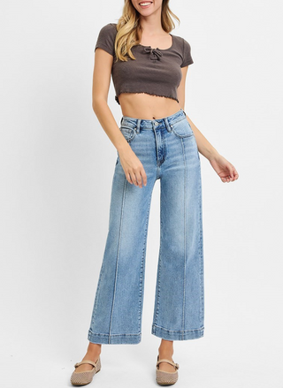 Woman wearing a brown crop top and blue jeans on a white background