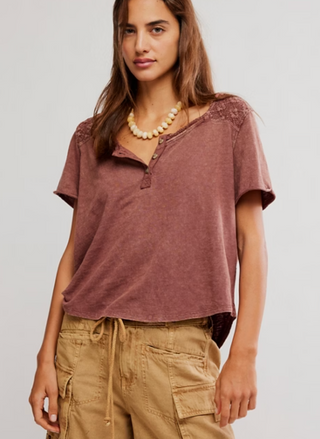 Woman wearing Free People Heirloom Henley in Canyon Sunset, featuring lace yoke on front and back, short sleeves, and relaxed fit, styled with tan cargo pants.