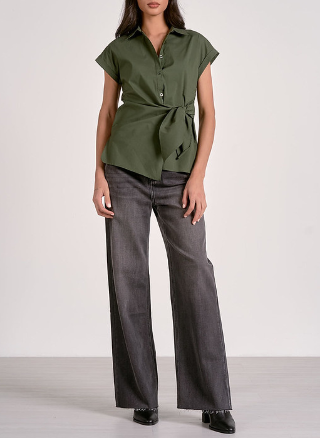Olive green short-sleeve button-up blouse with a collared neckline, front tie waist detail, and tailored fit, styled with dark wash jeans for a chic casual look.