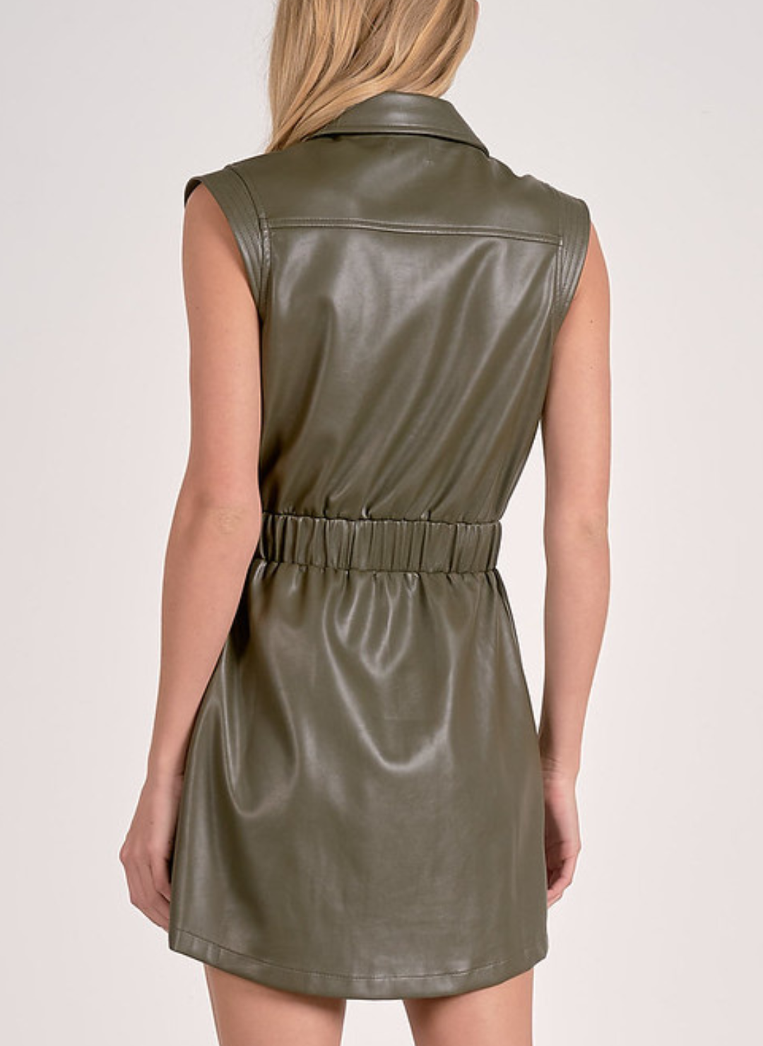 Back view of a model wearing the olive green faux leather mini dress, highlighting the elasticated waist and smooth back panel.
