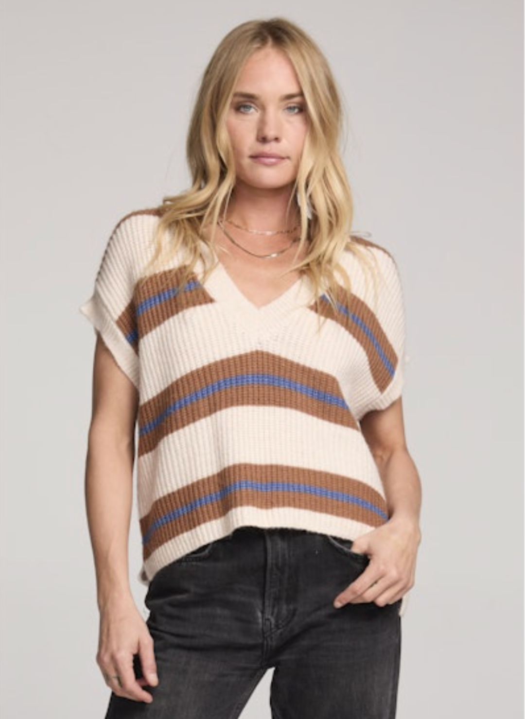 Saltwater Luxe Fitz Sweater Top in cream with camel and ocean-blue horizontal stripes, sleeveless V-neck ribbed knit with relaxed boxy fit, styled with black denim jeans for a casual chic look.