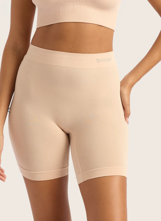 Beige shapewear shorts worn by a model on a plain background