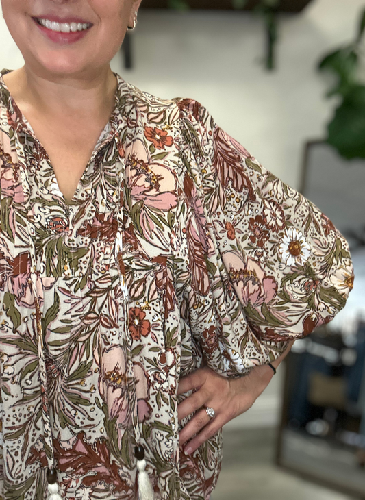 Person wearing a floral blouse with a blurred background