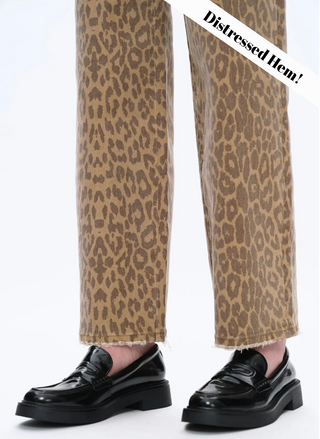 Close-up of raw hem on tan leopard print straight-leg jeans, frayed edge detail with black loafers.