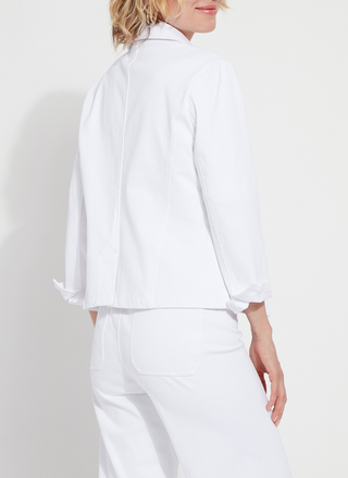 Back view of a woman wearing a crisp white Lyssé Della Stretch Denim Blazer with rolled sleeves, notched lapels, and front button closure. This tailored yet stretchy blazer is styled with matching white denim, offering a clean, polished boutique look perfect for work or weekend wear.