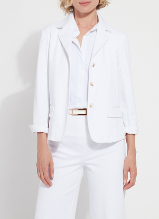 Woman wearing a crisp white Lyssé Della Stretch Denim Blazer with rolled sleeves, notched lapels, and front button closure. This tailored yet stretchy blazer is styled with matching white denim, offering a clean, polished boutique look perfect for work or weekend wear.