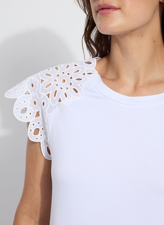 Woman wearing the Lyssé Katarina Eyelet Sleeve Trim Top in white; features embroidered floral eyelet cap sleeves, crew neckline, and a rounded shirttail hem. Lightweight and feminine, available at August Boutique Ripon.