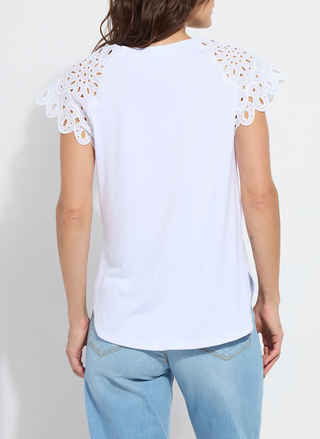 Woman wearing the Lyssé Katarina Eyelet Sleeve Trim Top in white; features embroidered floral eyelet cap sleeves, crew neckline, and a rounded shirttail hem. Lightweight and feminine, available at August Boutique Ripon.