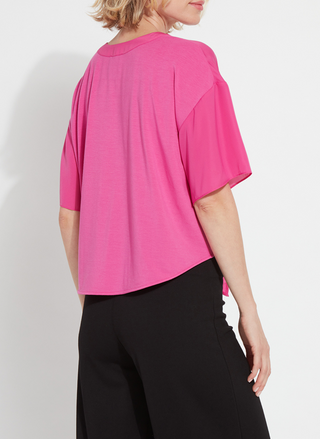 Back view of a woman wearing the Lyssé Cleo Tie Up Top in vibrant hot pink; features dolman short sleeves, v-neckline, and tie-front hem. Styled for comfort and polish, available at August Boutique Ripon.
