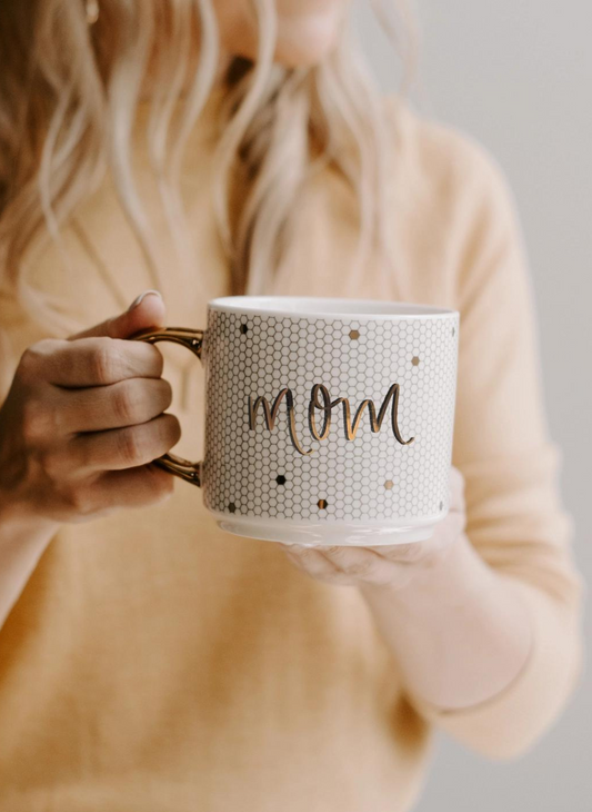 Model holding MOM Coffee Mug. Wearing a yellow crew neck in background. 