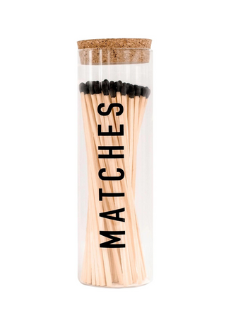 White background. Tall glass round canister for 7" matches.  Front of glass jar says "MATCHES" in black lettering.  Cork top.